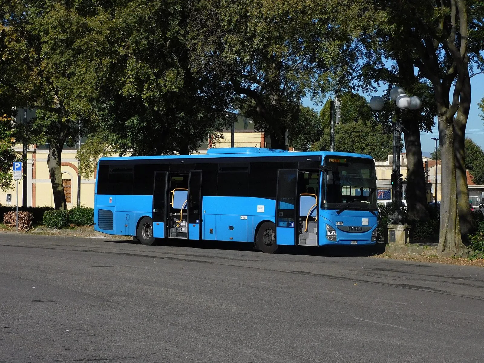 Autobus extraurbano azzurro di Autolinee Toscane in sosta sotto gli alberi a Firenze